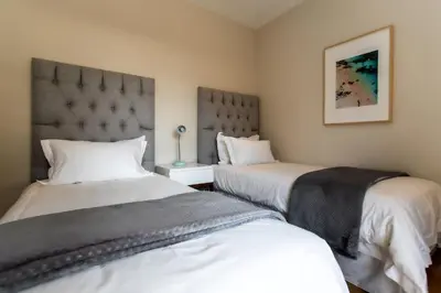a bedroom with two beds and a headboard at Sur La Mer in Hermanus