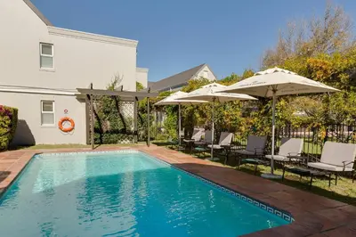 a swimming pool with chairs and umbrellas at Protea Hotel by Marriott Cape Town Mowbray in Cape Town