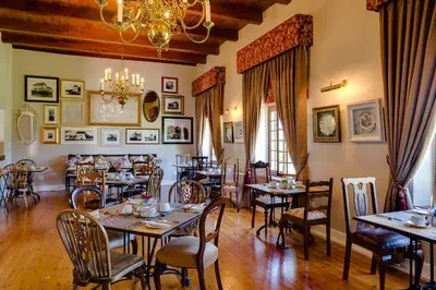 a dining room with tables and chairs and a chandelier at Protea Hotel by Marriott Cape Town Mowbray in Cape Town