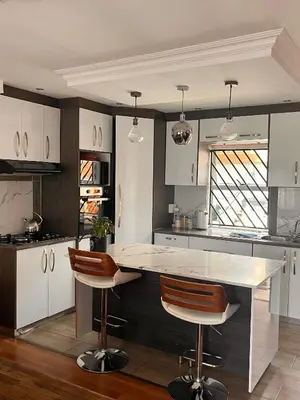 a kitchen with white cabinets and a island with bar stools at Self catering three bedroom in Cape Town