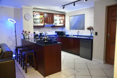 a kitchen with a bar with a sink and a counter at The Perfect Cape Town Retreat in Cape Town
