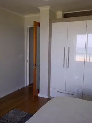 a bedroom with a white cabinet and a door at Beachfront Apartment at Seaspray in Blouberg in Bloubergstrand