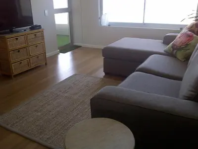 a living room with a couch and a tv at Beachfront Apartment at Seaspray in Blouberg in Bloubergstrand
