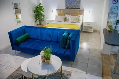 a blue couch in a living room with a bed at Optimum Stay Self Catering Accommodation - Deluxe Room in Cape Town