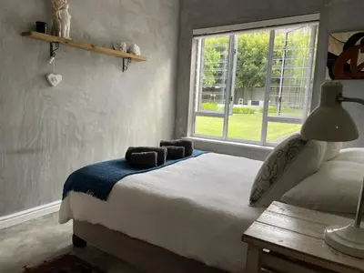 a bedroom with a bed and a window at Mosselberg Garden Gottage in Hermanus