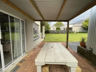 a wooden bench sitting on the porch of a house at Mosselberg Garden Gottage in Hermanus