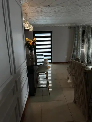 a living room with a table and chairs and a vase of flowers at Luxurious 4 bedroom Family Home in Cape Town