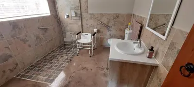 a bathroom with a sink and a shower and a chair at Riverbank in Tulbagh