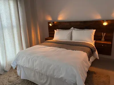 a bedroom with a bed with white sheets and a window at Modern 3 bedroom Urban Getaway in Cape Town