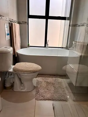 a bathroom with a tub and a toilet and a window at Modern 3 bedroom Urban Getaway in Cape Town
