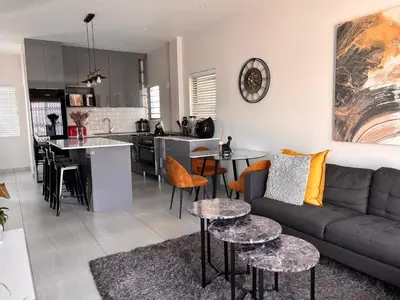 a living room and kitchen with a couch and tables at Modern 3 bedroom Urban Getaway in Cape Town