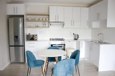 a kitchen with white cabinets and a table and chairs at Coastal Beach & Mountain Retreat in Cape Town
