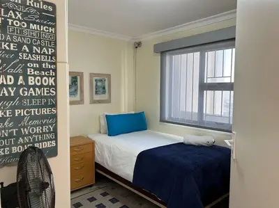 a small bedroom with a bed and a window at Nautica by the Beach in Cape Town