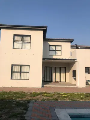 a white house with black windows at Five bedrooms holiday home in Cape Town