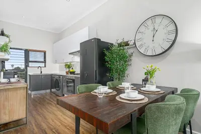 a dining room with a table and a clock on the wall at Atlantic Port 10 by Host Agents in Cape Town