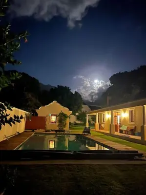 a house with a swimming pool at night at Klein La Cotte Garden Cottage in Franschhoek
