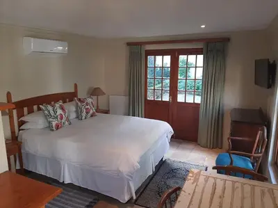 a bedroom with a large white bed and a window at Klein La Cotte Garden Cottage in Franschhoek