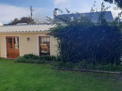 a small white house with a door in a yard at Klein La Cotte Garden Cottage in Franschhoek
