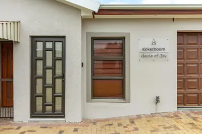 a white house with a door and a sign on it at House of joy in Cape Town