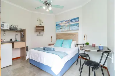 a bedroom with a bed and a table and a kitchen at House of joy in Cape Town