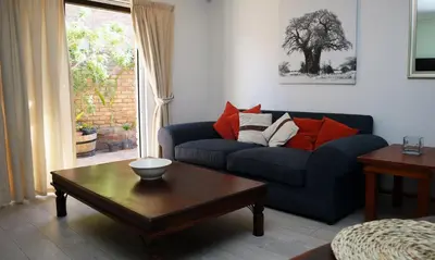 a living room with a blue couch and a coffee table at Strand Beach Townhouse Self Catering in Cape Town