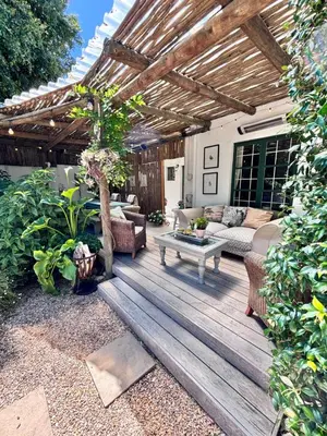 a patio with a wooden deck with a couch and a table at Garden oasis in the village in Franschhoek