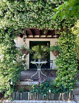 a patio with a table and flowers on a deck at Garden oasis in the village in Franschhoek