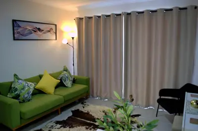 a living room with a green couch in front of a window at Camden Stay - Entire Unit - Cape Town in Cape Town