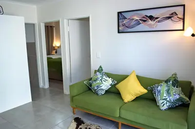 a living room with a green couch with pillows on it at Camden Stay - Entire Unit - Cape Town in Cape Town