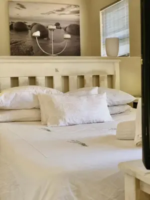 a bed with white sheets and pillows in a bedroom at #SilverSands Coastal Retreat in Betty's Bay in Bettyʼs Bay