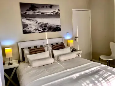 a bedroom with a large white bed with two lamps at #SilverSands Coastal Retreat in Betty's Bay in Bettyʼs Bay