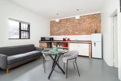 a living room with a couch and a table at 1Bed Flat, Braai, AC, Walking Distance from Blouberg Beachfront in Cape Town