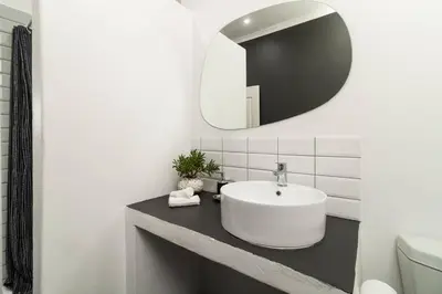 a white bathroom with a sink and a mirror at 1Bed Flat, Braai, AC, Walking Distance from Blouberg Beachfront in Cape Town
