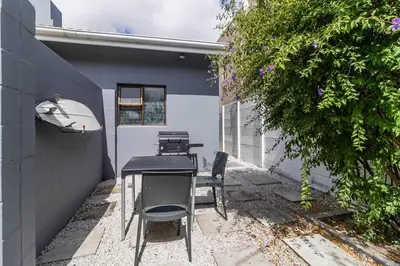 a table and chairs in the courtyard of a house at 1Bed Flat, Braai, AC, Walking Distance from Blouberg Beachfront in Cape Town