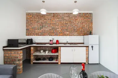 a kitchen with a brick wall and white appliances at 1Bed Flat, Braai, AC, Walking Distance from Blouberg Beachfront in Cape Town