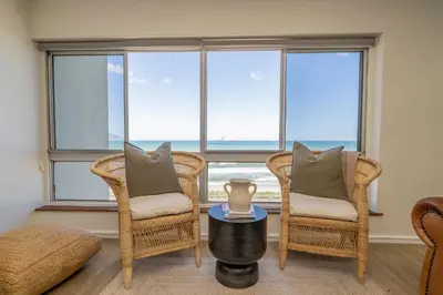 a living room with two chairs and a table and a window at 2 Bedroom Apartment - Blouberg Beachfront in Cape Town
