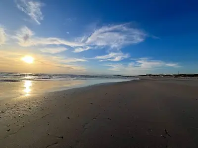 a beach with the sun reflecting on the sand at Cosy Home with an Ocean Breath! in Cape Town