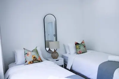 two beds in a room with a mirror at Luxury Poolside Villa Irene in Cape Town