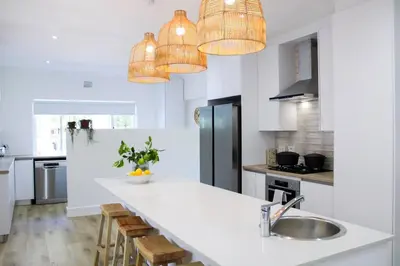 a kitchen with a sink and a counter with chairs at Luxury Poolside Villa Irene in Cape Town