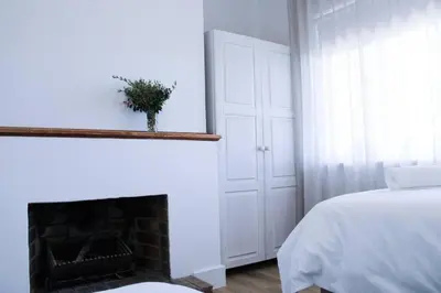 a white bedroom with a fireplace and a bed at Luxury Poolside Villa Irene in Cape Town