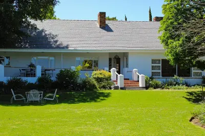 a white house with a table and chairs in the yard at Luxury Poolside Villa Irene in Cape Town