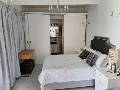 a bedroom with a bed and a chandelier at Cosy Cottage Cape Town in Cape Town