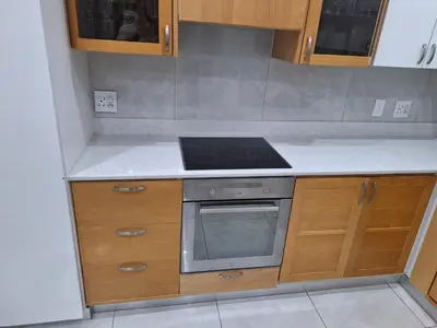 a kitchen with wooden cabinets and a stove top oven at Cosy Cottage Cape Town in Cape Town
