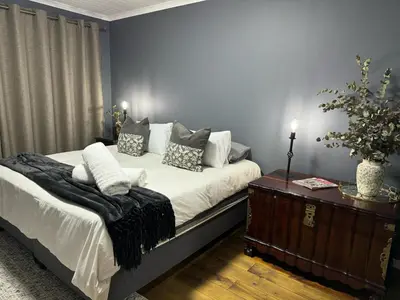 a bedroom with a bed with pillows and a table at Ocean Breath Apartment in Strand