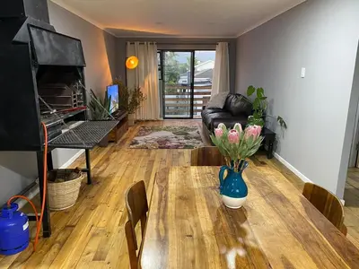a living room with a table with a vase of flowers on it at Ocean Breath Apartment in Strand