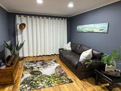 a living room with a leather couch and a rug at Ocean Breath Apartment in Strand