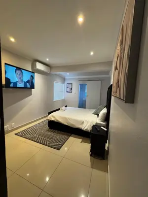 a bedroom with a bed and a flat screen tv at Canary Guest house in Cape Town