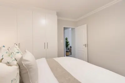 a white bedroom with a bed with white walls at Elegant apartment near beach in Cape Town