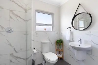 a bathroom with a toilet and a sink and a mirror at Elegant apartment near beach in Cape Town