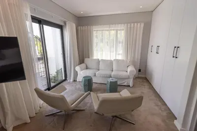 a living room with two chairs and a couch and a tv at Waveren's Nest in Cape Town